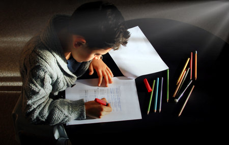 Teenager boy doing homework at home and writing notes.
