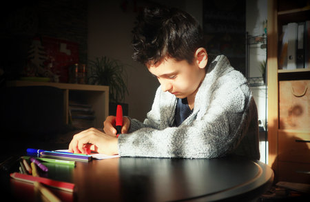 Teenager boy doing homework at home and writing notes.