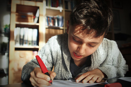 Teenager boy doing homework at home and writing notes.の写真素材