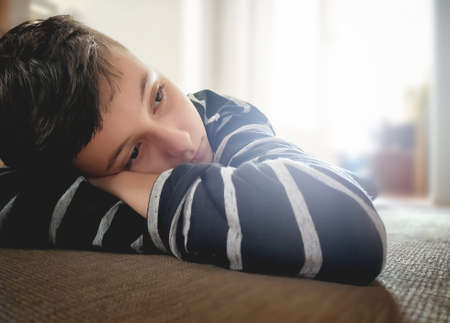 Close up Pensive Boy Leaning his Face on his Handsの写真素材