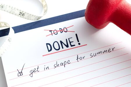 Text "Get in shape for summer" in the notebook with red dumbbells and measuring tape. Get fit for summer concept, close up.の写真素材