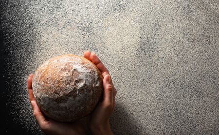 Female hands hold fresh baked bread flat lay with copy space. Flour texture. Gluten free healthy diet concept.の写真素材