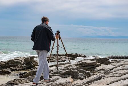 Young man setting up tripod for shooting photography and video making. Travel photography concept....