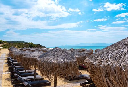 Idyllic beach with comfort Lounge chairs and straw umbrellas. Comfort summer vacation conceptの写真素材