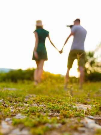 Couple walking at fueld holding hands while man photoshooting a woman. Selective focusの写真素材