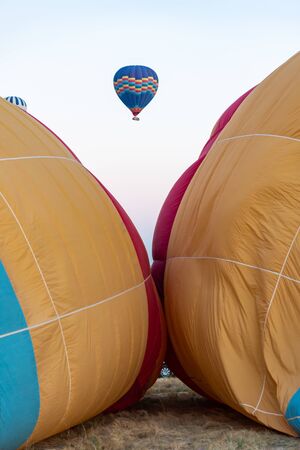 Vertical closeup view of two hot air balloons inflating and one flying in between.の写真素材