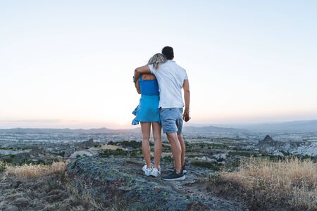 Young loving heterosexual couple hugging and looking at sunset in Cappadocia.の写真素材
