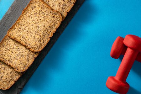 Whole grain protein low carb bread with dumbbells, view from top, copy space. Fitness bread concept.の写真素材