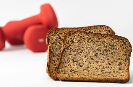 Fitness protein bread and unfocused red dumbbells on background. Helthy lifestyle sports concept.の写真素材