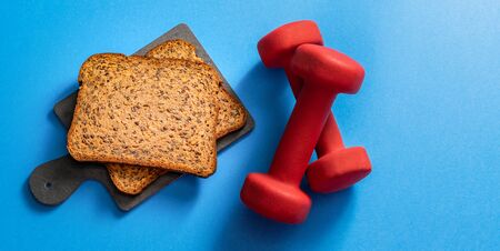 Whole grain protein low carb bread with dumbbells, view from top, copy space. Fitness bread concept.の写真素材