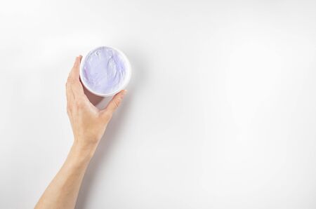 Woman's hands holding purple moisturizing cream with bakuchiol ingredient. Flat lay, copy space.の写真素材