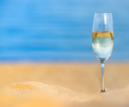 Glasses of champagne on sandy beach against blue sea.  Celebrate summer concept. Selective focus, blurred background, space for textの写真素材