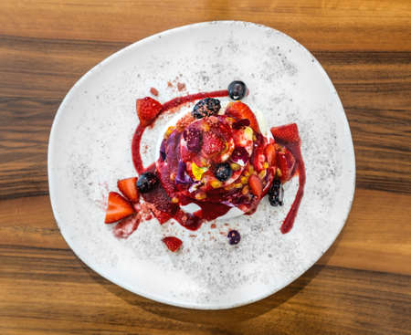 Gourmet strawberry Pavlova cake with fresh berries topping and layers of whipped cream and meringue served on a plate,の写真素材