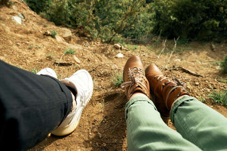 Legs of couple travelers sitting on a high mountain.
