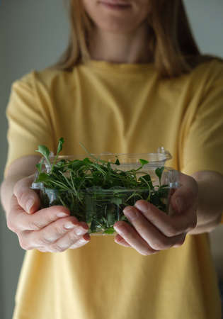 Woman holding plastic container with edible broccoli sprouts.の写真素材