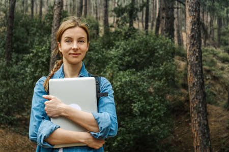 Woman in forest holding laptop.の写真素材
