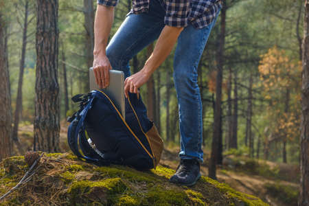 Man in forest with laptop and backpack.の写真素材