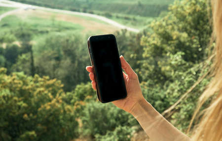 Woman holding smartphone with blank screen.