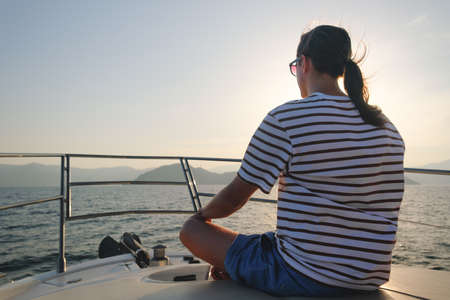 Young man sailing on luxury yacht at sunset.の写真素材