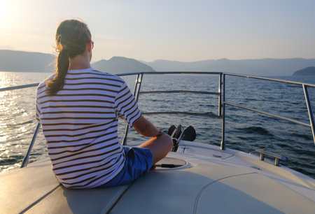 Young man sailing on luxury yacht at sunset.の写真素材