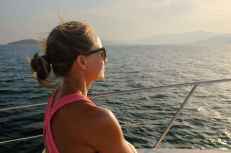 Woman sailing on luxury yacht at sunset.