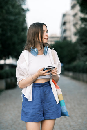 Portait of woman ith smartphone and headphones outdoor