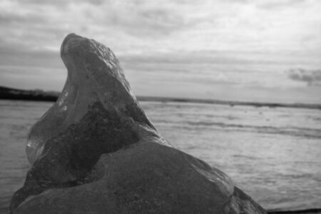 Some pieces of ice in front of the open sea at JÃ¶kulsÃ¡rlÃ³n, in the south Iceland, on a slightly cloudy summer day in black and whiteの写真素材