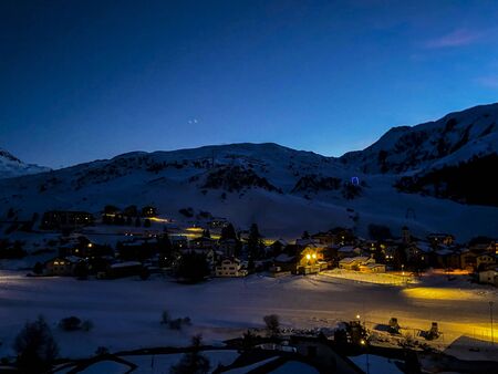 Colorful sunset on a cloudy winter day over a snowy village in the Swiss Alps