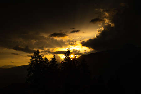 A silhouette before a colorful sunset after a thunderstorm in the Swiss Alps