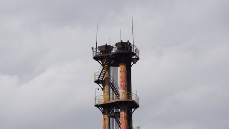 Abandoned industrial chimney against cloudy sky. Industrial background.の写真素材