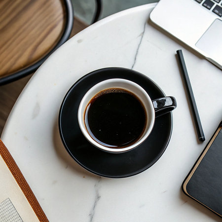 Coffee cup with notebook and laptop on table in coffee shopの素材