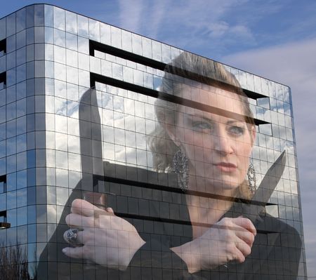 cut throat business woman with knives reflected in office buildingの写真素材