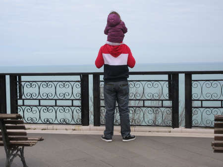 A young girl looks at the sea from the promenade.の写真素材