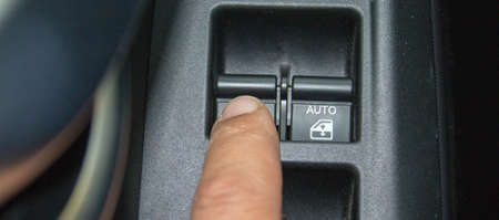 Image of a finger pressing the button to close the car window to reduce fuel consumption. Reference...
