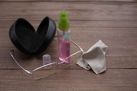 Picture of a pair of eyeglasses with their case, a patch and a bottle of spray. Reference how to clean the glassesの写真素材