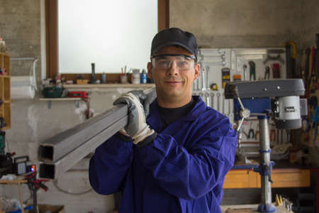 Picture of a handyman blacksmith in his workshop carrying iron bars. Do-it-yourself work.の写真素材