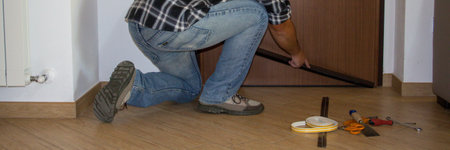 Handyman installing a dust seal on the house door. Better thermal insulation and cleaning of the floor. Horizontal bannersの写真素材