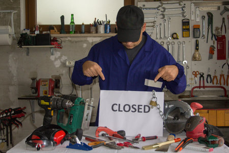 Craftsman in his workshop with a bench with tools in front of it and a sign with the words closed...