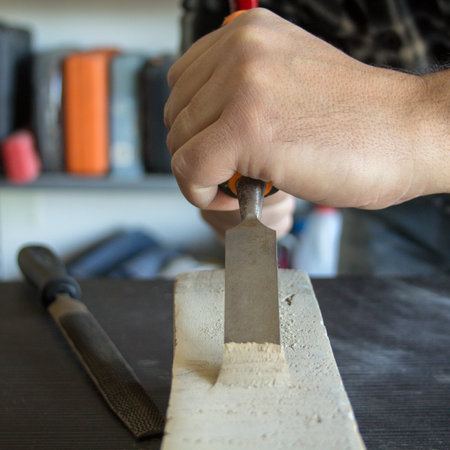 Image of a handyman craftsman's hands holding a carpenter's hammer and chisel while doing some work...