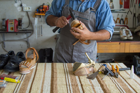 Image of a shoemaker repairing the sole of a woman's shoe. Manual and do-it-yourself workの写真素材