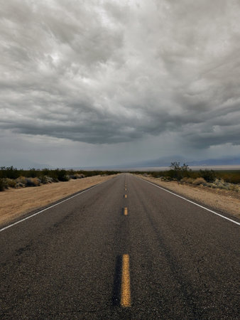 Road in the desert with stormy clouds and stormy sky.