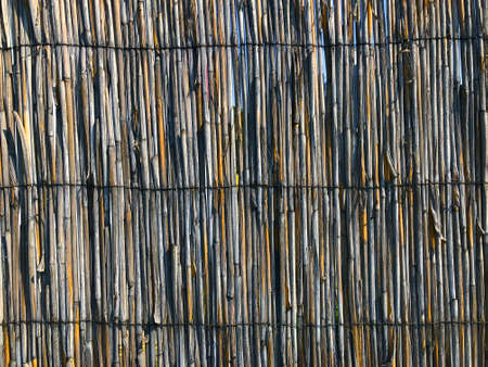 Old brushwood fence. Wicker fence made of willow branches. Beautiful natural background. Wicker fence background. Wall of wicker natural branches. Brown natural background.の写真素材