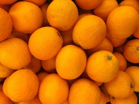 Orange is the same fruit as grapefruit. there are many, stacked in a crate that looks bright and...