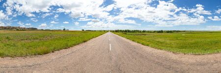 The straight asphalt road with meadows on both sidesの写真素材