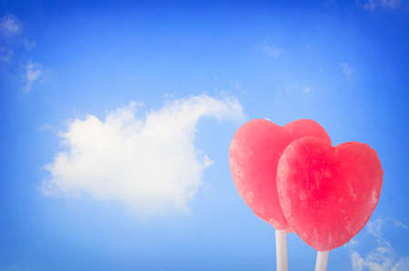 Candy hearts on the blue sky with cloudの写真素材