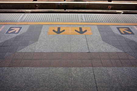 Arrow sign wait electric train behind yellow lineの写真素材