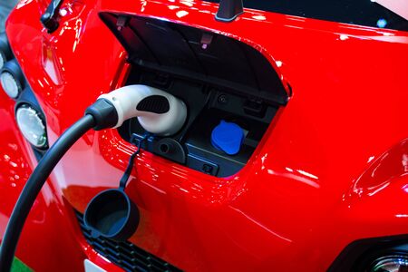 Red electric car at charging in stationの写真素材