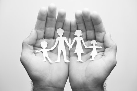 Paper family in hands. Black and white photo. Family insurance concept.の写真素材