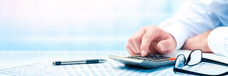 Accountant working with calculator at office.
