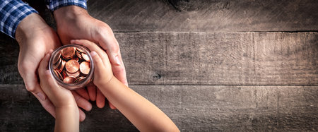 Hands Of Father Giving Jar Of Coins To Child On Wooden Table Background - Inheritance / Parent...